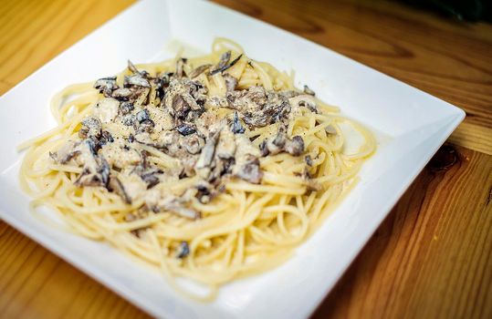 porcini mushroom and sour cream sauce spaghetti dish on wooden table