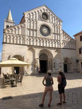 Two tourists looking at the Saint Anastasia romanesque cathedral in Zadar Croatia