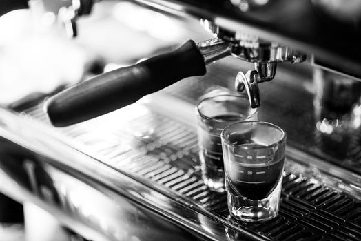 making espresso coffee BW black and white close up detail with modern cafe machine and glasses