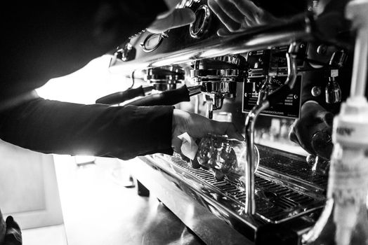 making espresso coffee BW black and white close up detail with modern cafe machine and glasses