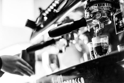 making espresso coffee BW black and white close up detail with modern cafe machine and glasses