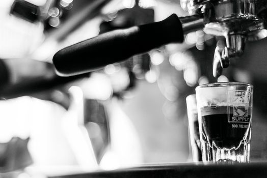 making espresso coffee BW black and white close up detail with modern cafe machine and glasses