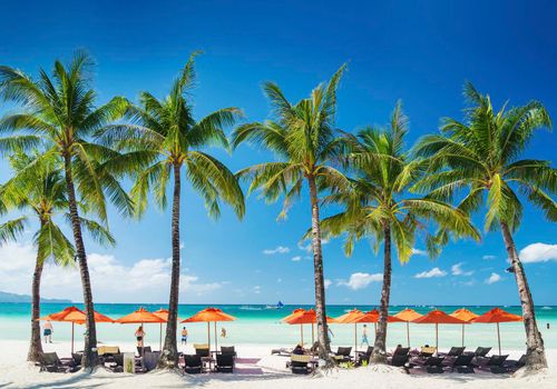 white beach lounge bar chairs and umbrellas on boracay tropical island in philippines