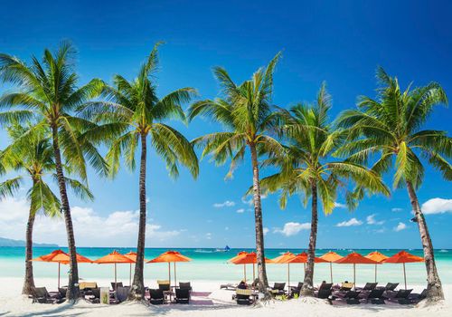 white beach lounge bar chairs and umbrellas on boracay tropical island in philippines