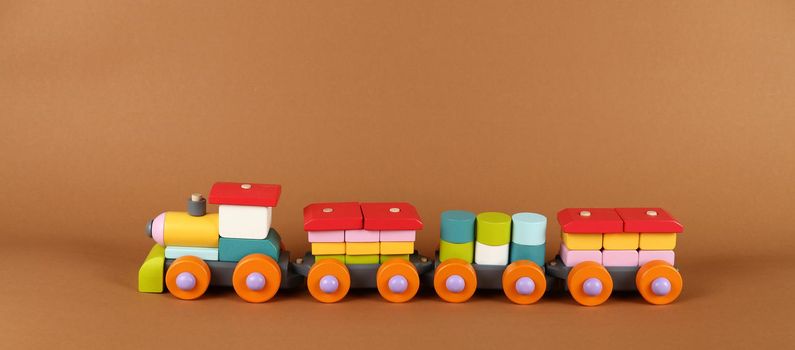 Close up one wooden painted colorful toy train on background of brown paper, high angle, side view