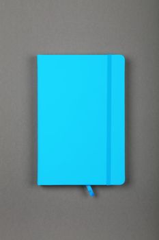 One closed blue faux leather cover notebook on grey paper background, flat lay, directly above