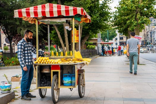 Man selling grilled corn from cart on the summer Istanbul street. Turkish street food business.