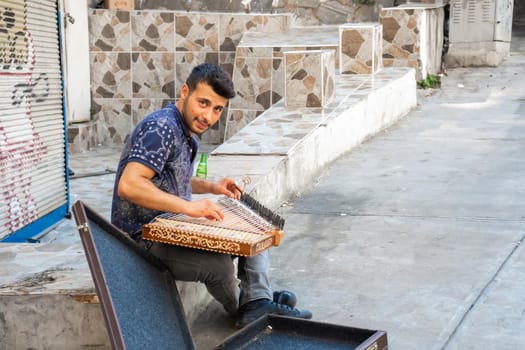 A young artist play music on qanun on the Istanbul city streets to get some money.