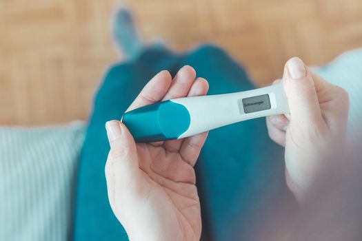 Woman hand holding pregnancy test, result is pregnant, “Schwanger”