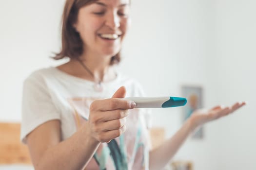 Happy mother holding pregnancy test in her hands, result is pregnant, “Schwanger”