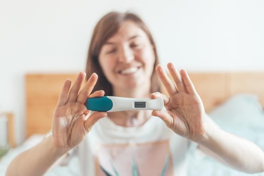 Happy mother holding pregnancy test in her hands, result is pregnant, “Schwanger”