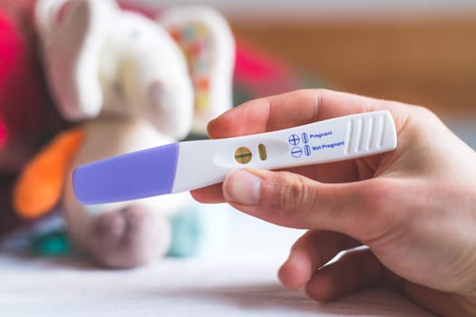 Woman hand holding pregnancy test, result is pregnant