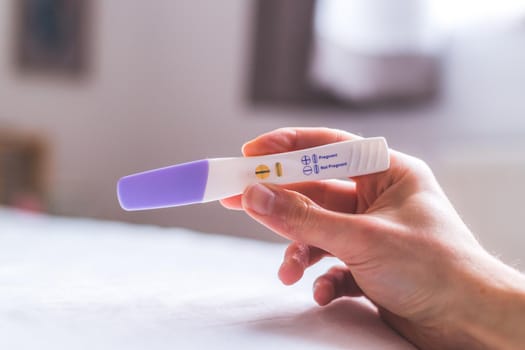 Woman hand holding pregnancy test, result is pregnant