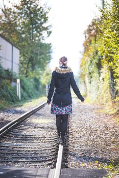 Girl waking on abandoned railroad, autumn