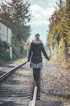 Girl waking on abandoned railroad, autumn