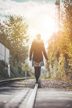 Girl waking on abandoned railroad, autumn