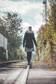 Girl waking on abandoned railroad, autumn