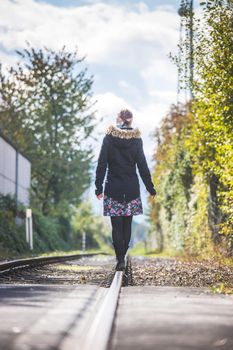 Girl waking on abandoned railroad, autumn