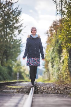 Girl waking on abandoned railroad, autumn