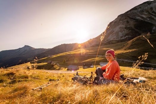 Woman in sportswear is enjoying the sunset in the mountains: sitting on the ground and enjoying the view. Alpes, Austria