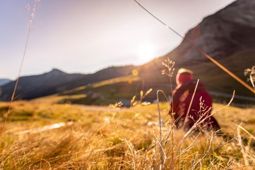 Woman in sportswear is enjoying the sunset in the mountains: sitting on the ground and enjoying the view. Alpes, Austria