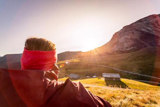 Woman in sportswear is enjoying the sunset in the mountains: sitting on the ground and enjoying the view. Alpes, Austria