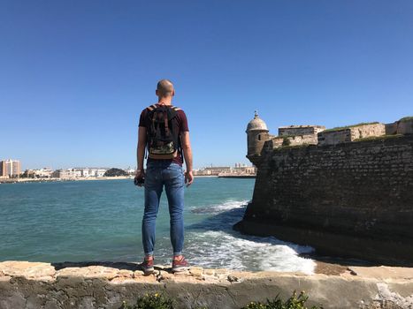 Man standing at the wall of the Castle of San Sebastian in Cadiz Spain