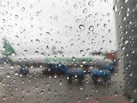 Looking through an airplane window with raindrops to an Transavia airplane at Schiphol Airport in The Netherlands