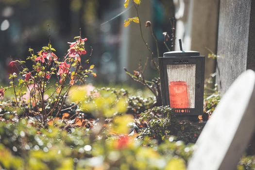 Candle in an iron lantern on a grave at a cemetery