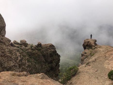 Man standing a rock at the Roque Nublo a volcanic rock on the island of Gran Canaria