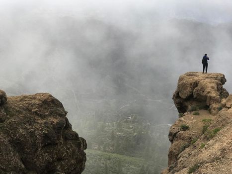 Man taking a picture at the Roque Nublo a volcanic rock on the island of Gran Canaria