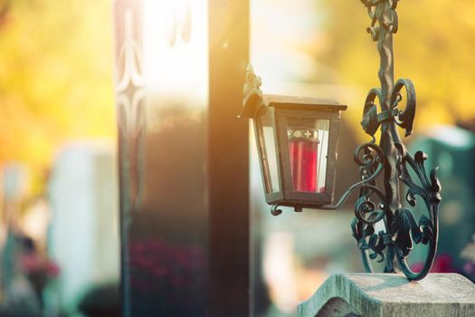 Candle in an iron lantern on a grave at a cemetery