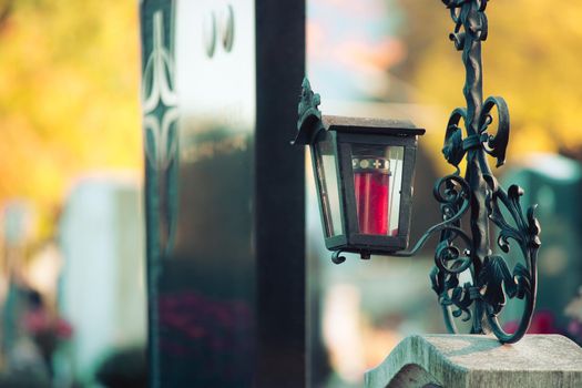 Candle in an iron lantern on a grave at a cemetery