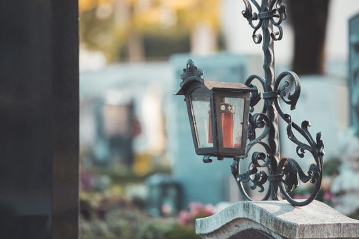 Candle in an iron lantern on a grave at a cemetery