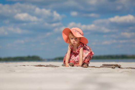 A little girl in a beautiful sarafna plays in the sand on the beach.