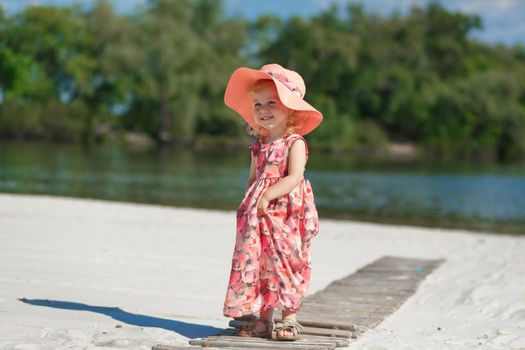 A little girl in a beautiful sarafna plays in the sand on the beach.