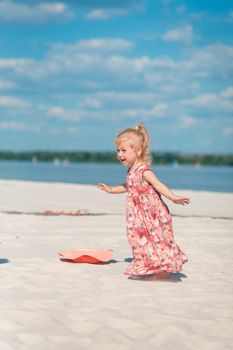 A little girl in a beautiful sarafna plays in the sand on the beach.