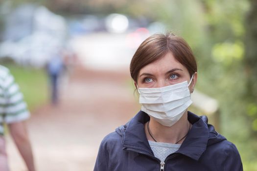 Young woman outdoors wearing a face mask. Corona and flu season.