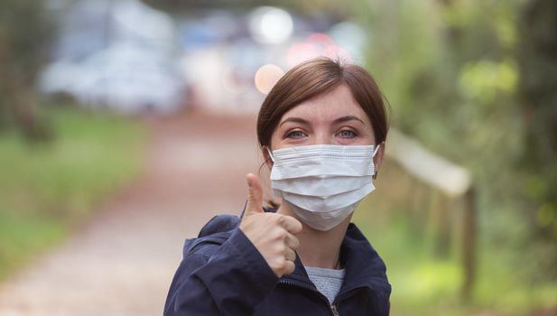 Young woman outdoors wearing a face mask. Corona and flu season.