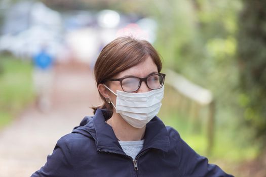 Young woman outdoors wearing a face mask and glasses, tarnished glasses