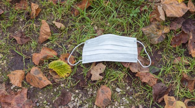 Environmental pollution concept: Single use face mask on the floor outdoors, waste