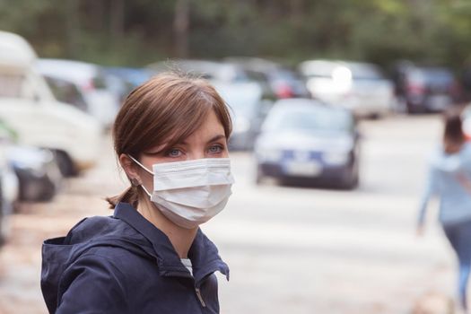 Young woman outdoors wearing a face mask. Corona and flu season.