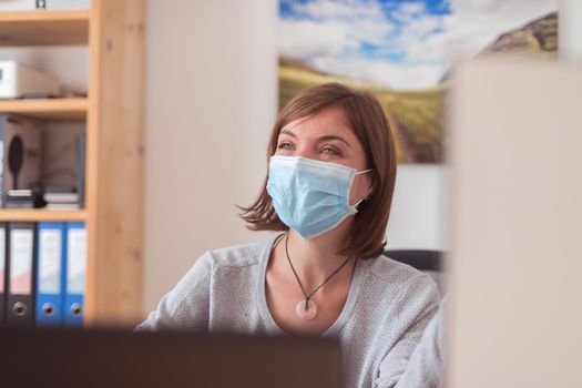 Young woman wearing face mask is working in the office during corona crisis