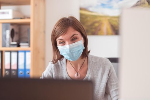 Young woman wearing face mask is working in the office during corona crisis