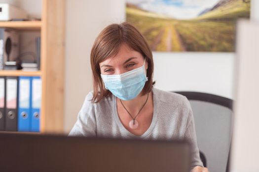 Young woman wearing face mask is working in the office during corona crisis