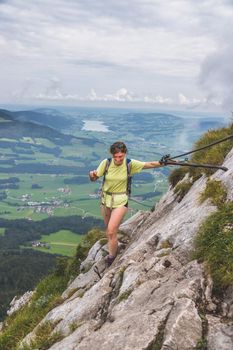 Young slim backpacker tourist girl climbing on rocky mountain, Austria
