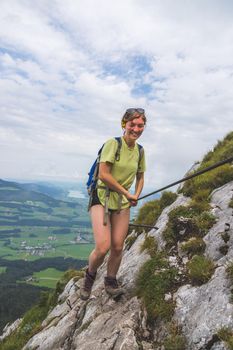 Young slim backpacker tourist girl climbing on rocky mountain, Austria