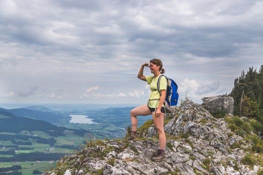 Young slim backpacker tourist girl is enjoying the view on rocky mountain, Austria