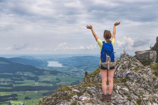 Young slim backpacker tourist girl is enjoying the view on rocky mountain, Austria