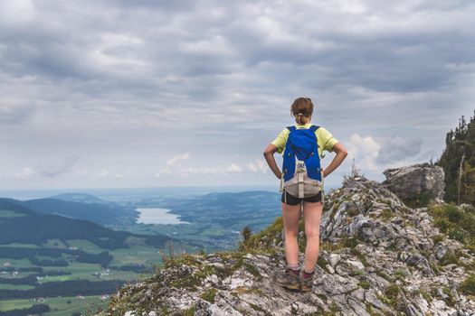 Young slim backpacker tourist girl is enjoying the view on rocky mountain, Austria